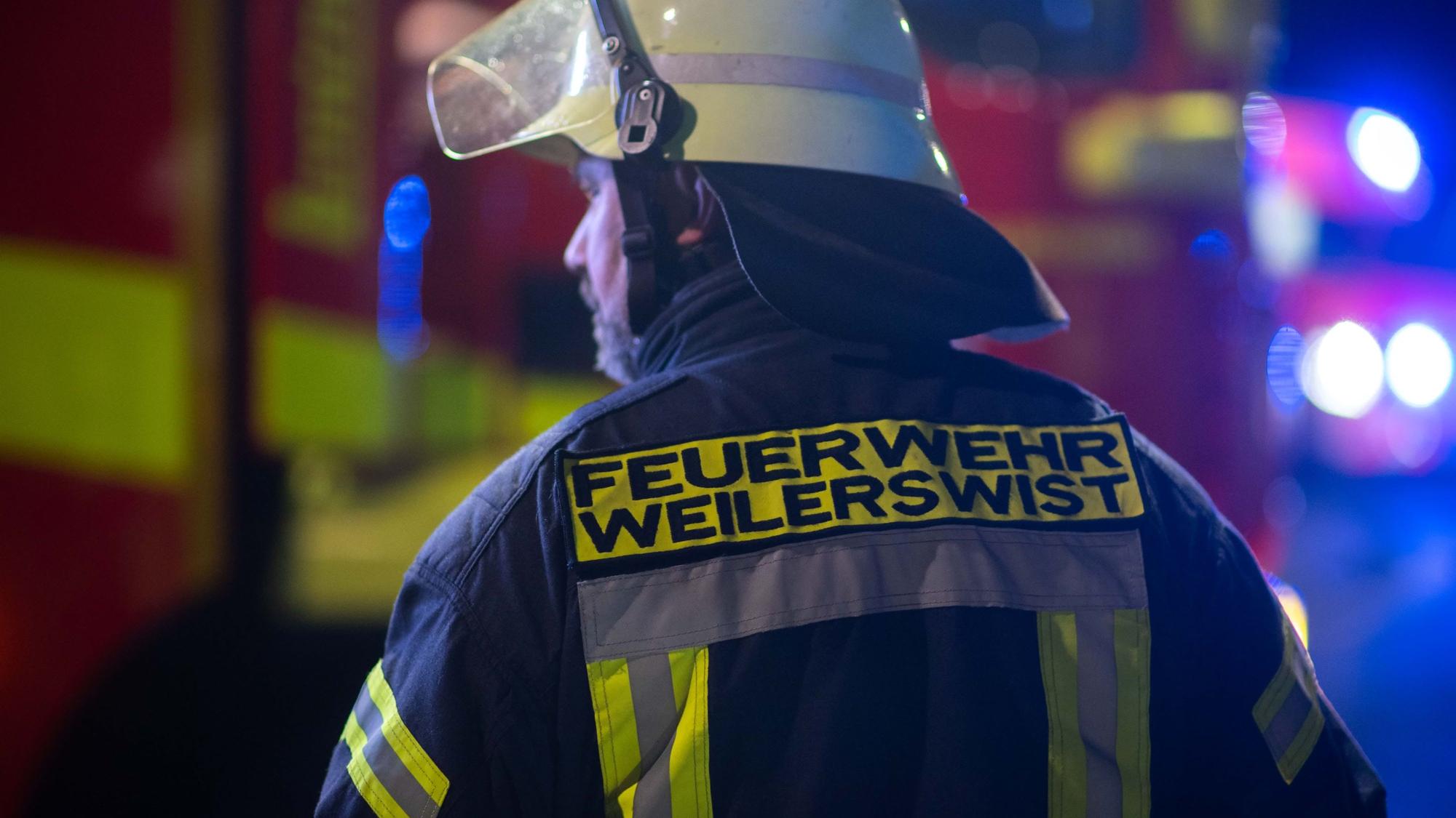 Ein Feuerwehrmann der Weilerswister Feuerwehr sichert in der Dunkelheit eine Unfallstelle ab.