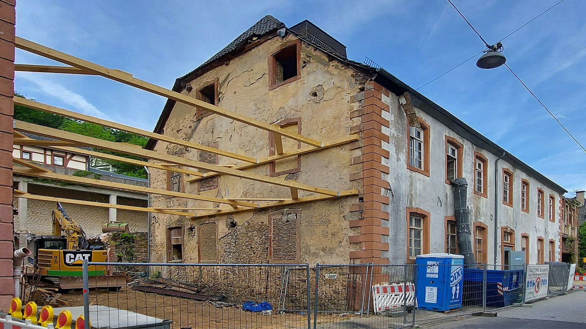 Vor einem alten Haus, das umgebaut wird, stehen Container.