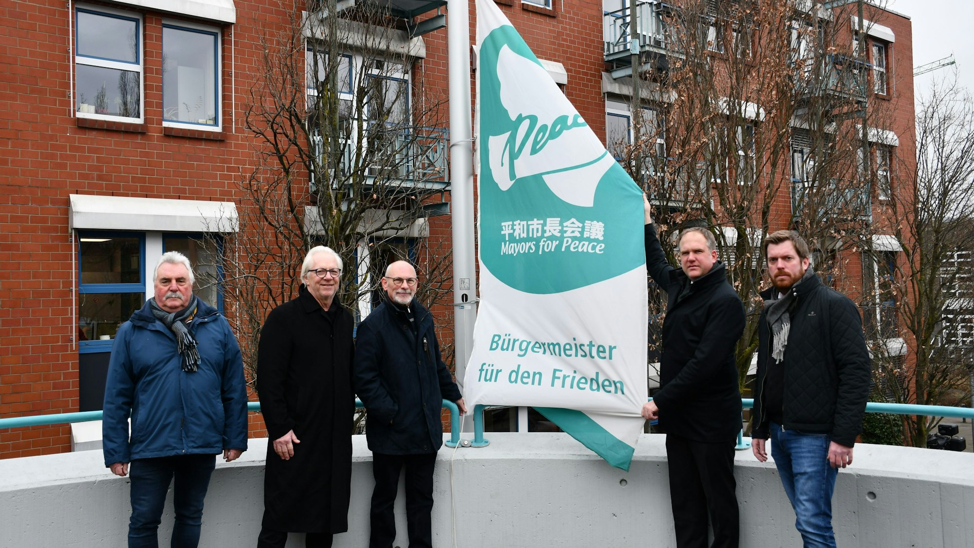 Das Foto zeigt, wie unter anderem Hürths Bürgermeister Dirk Breuer die „Mayors for Peace“-Flagge hisst.