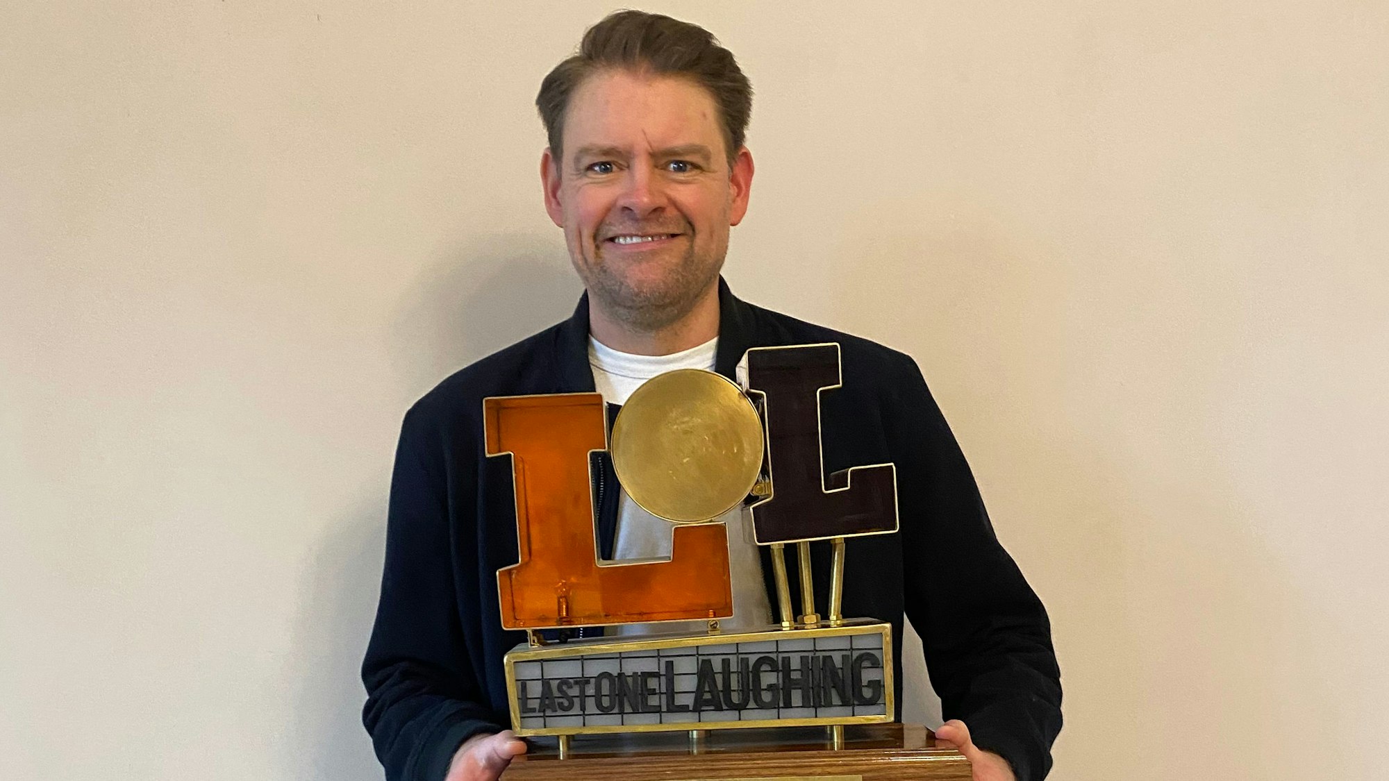 Max Giermann hält seinen LOL Pokal in die Kamera.