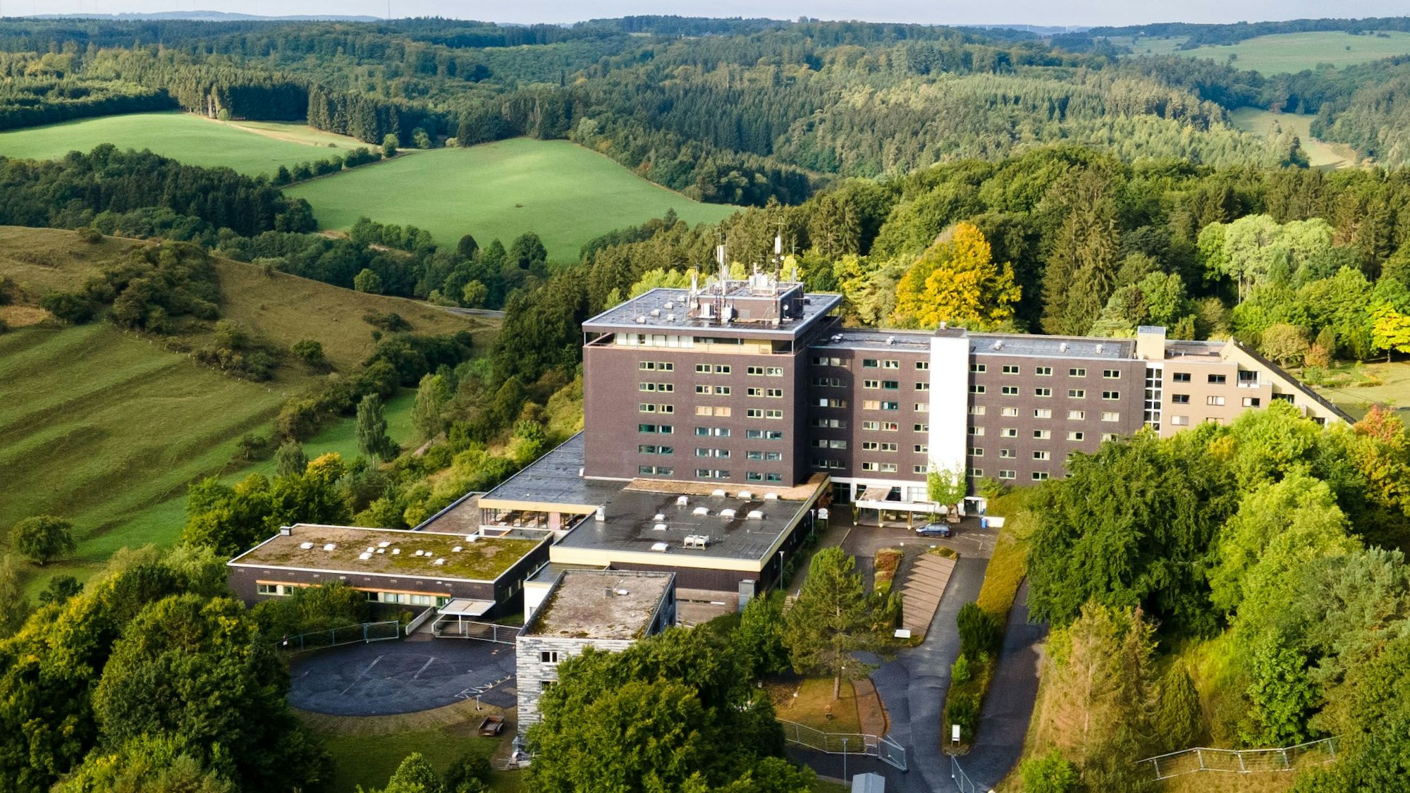 Das große Gebäude der früheren Eifelhöhen-Klinik in Marmagen, die jetzt als Unterkunft für Geflüchtete genutzt wird, liegt am Ortsrand von Marmagen und ist von idyllischer Natur umgeben.