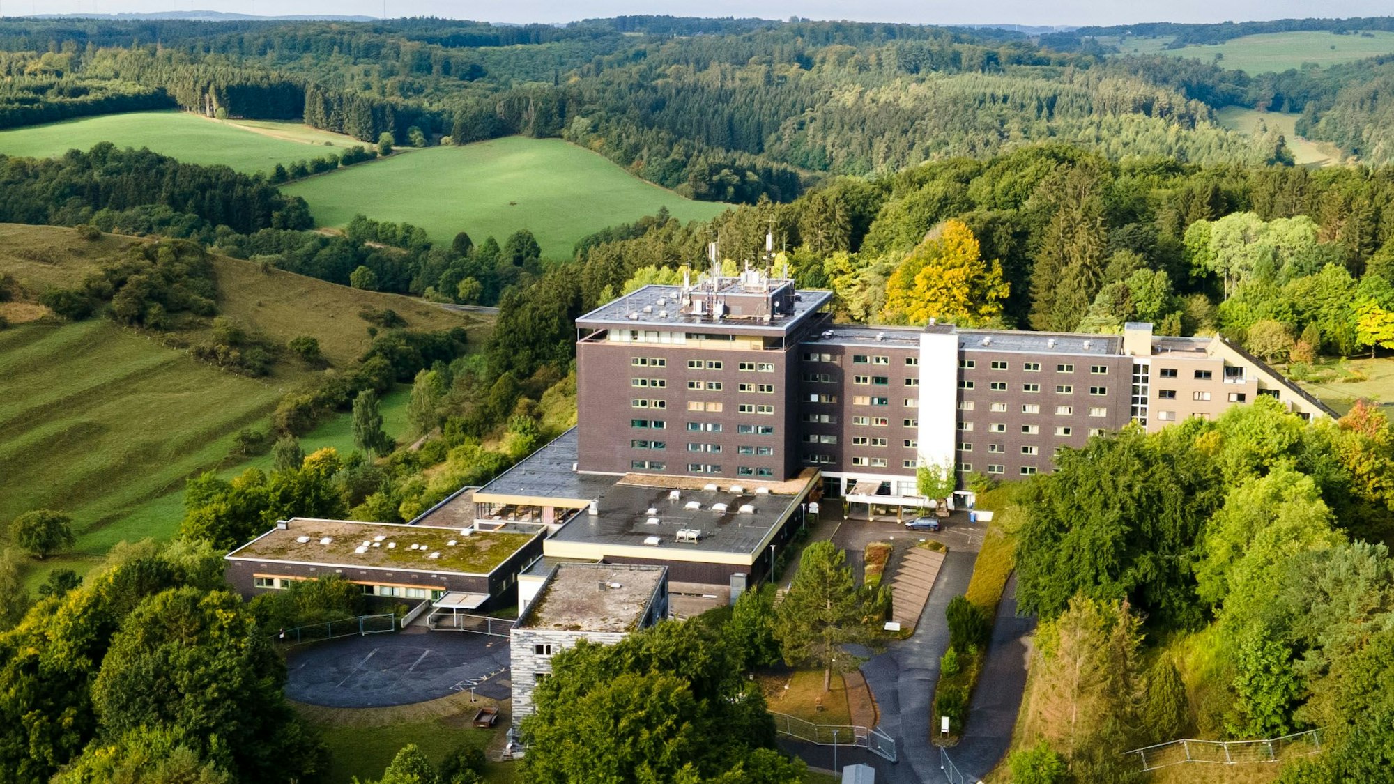 Das große Gebäude der früheren Eifelhöhen-Klinik in Marmagen, die jetzt als Unterkunft für Geflüchtete genutzt wird, liegt am Ortsrand von Marmagen und ist von idyllischer Natur umgeben.