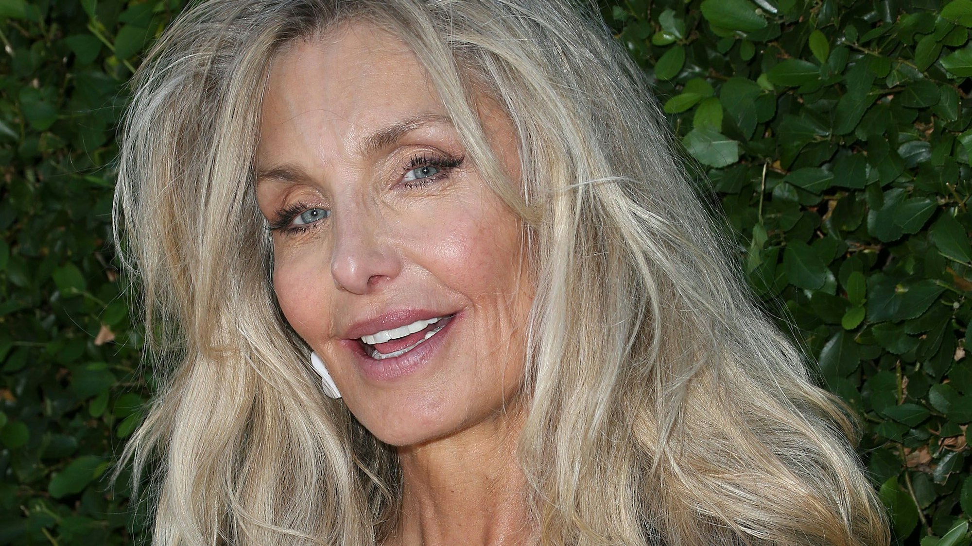 Heather Thomas vor grünen Blättern.