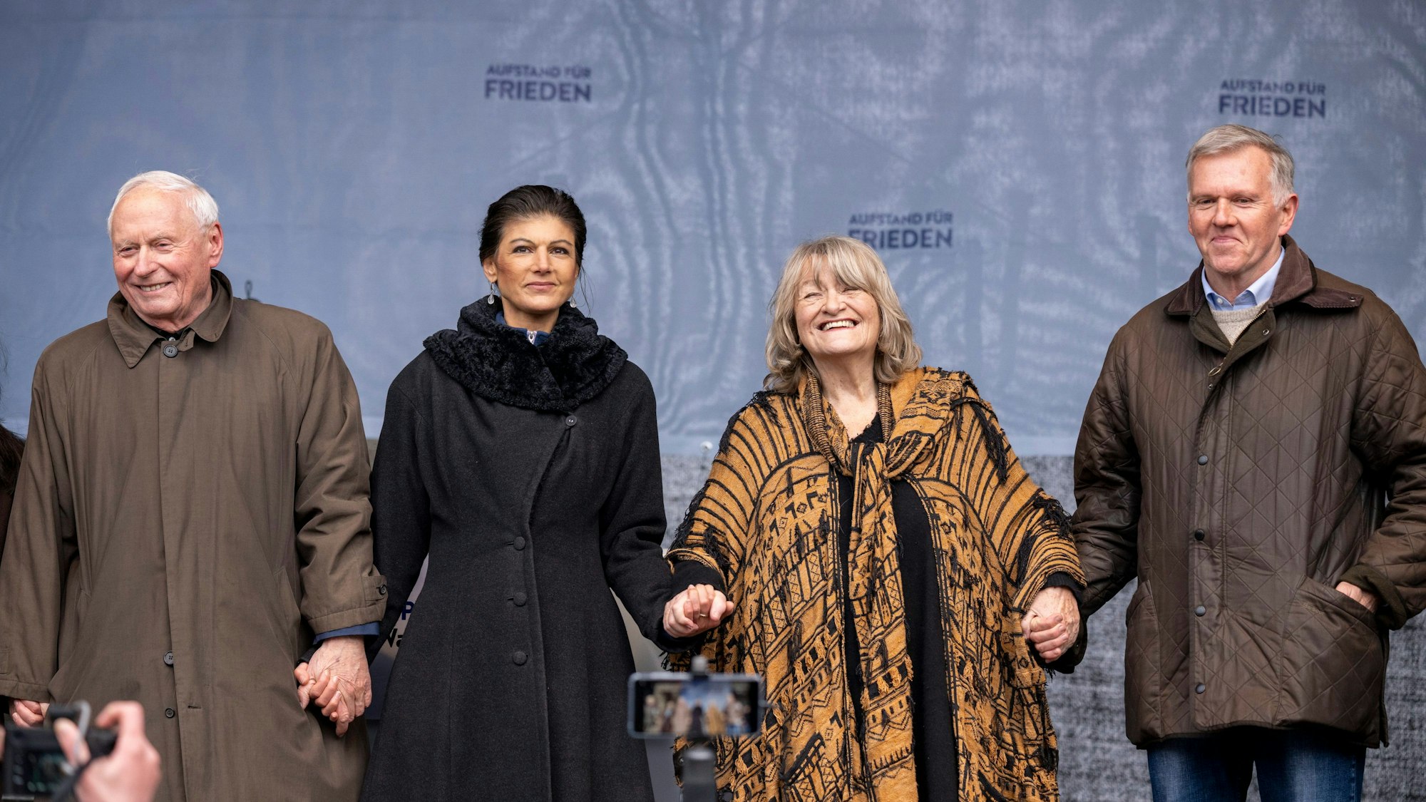 25.02.2023, Berlin: Oskar Lafontaine (l-r), Sahra Wagenknecht (Die Linke), Alice Schwarzer, Frauenrechtlerin, und Brigadegeneral a.D. Erich Vad stehen beim Abschluss der Demonstration auf der Bühne. Am Brandenburger Tor in Berlin haben sich mehrere Tausend Menschen zu einer Kundgebung für Verhandlungen mit Russland im Ukraine-Krieg versammelt. Foto: Monika Skolimowska/dpa +++ dpa-Bildfunk +++