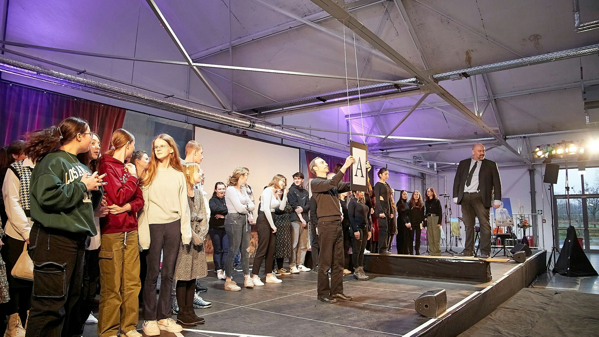 Schauspieler Pierre Stoltenfeldt steht mit den Jugendlichen auf der Bühne.