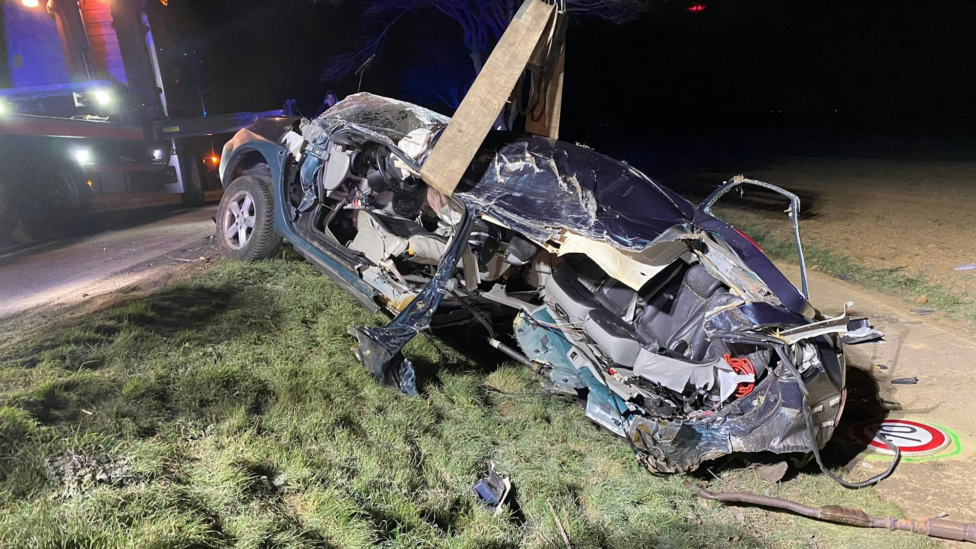 Ein Auto liegt völlig demoliert am Straßengraben.