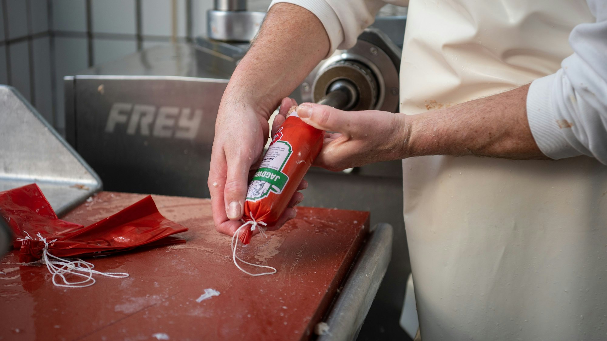 Die Wurst wird in einen Kunstdarm gepresst. Der Ausschnitt ist auf die Hände begrenzt.