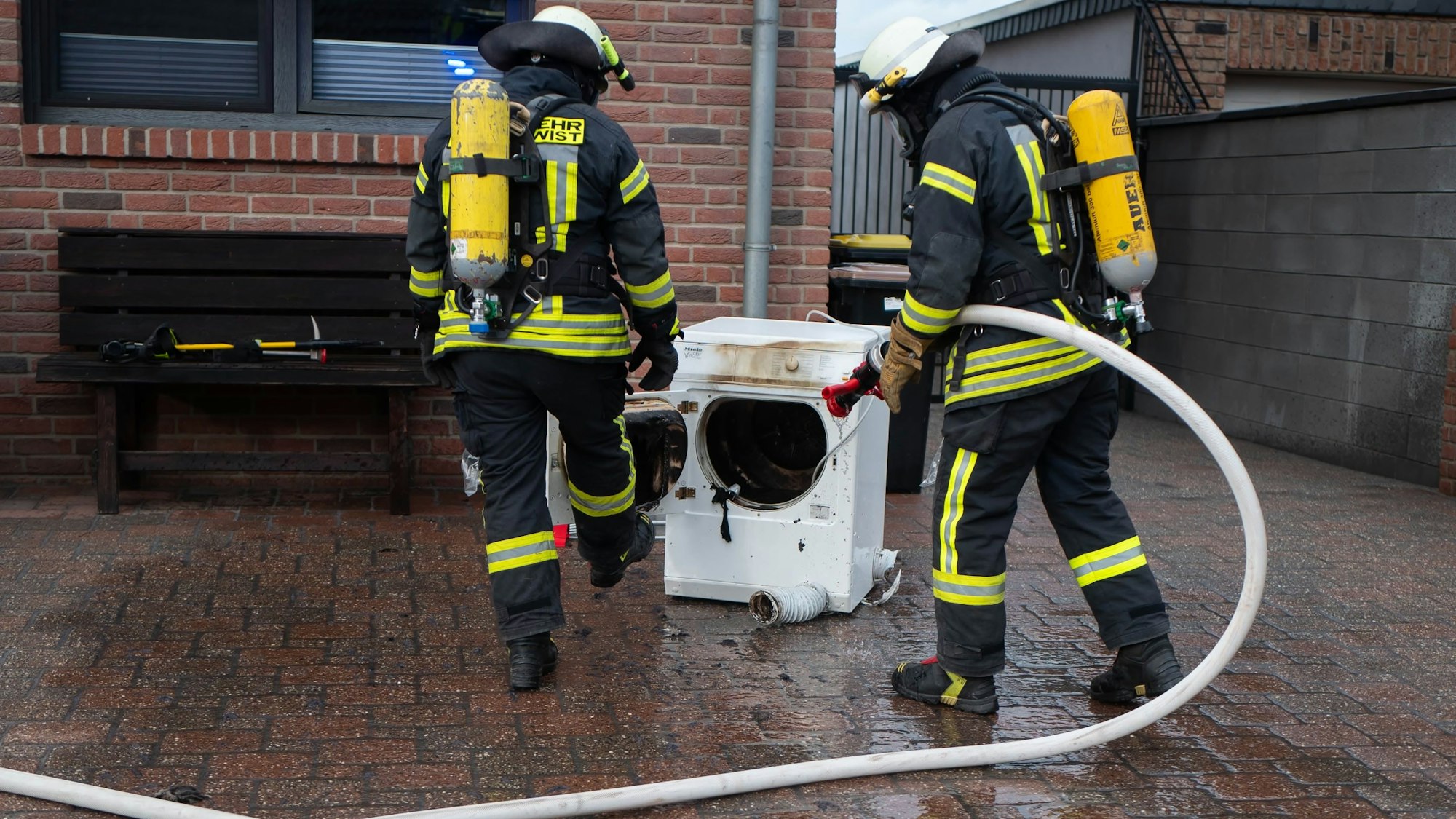 Zwei Feuerwehrmänner der Weilerswister Feuerwehr löschen einen Trockner.
