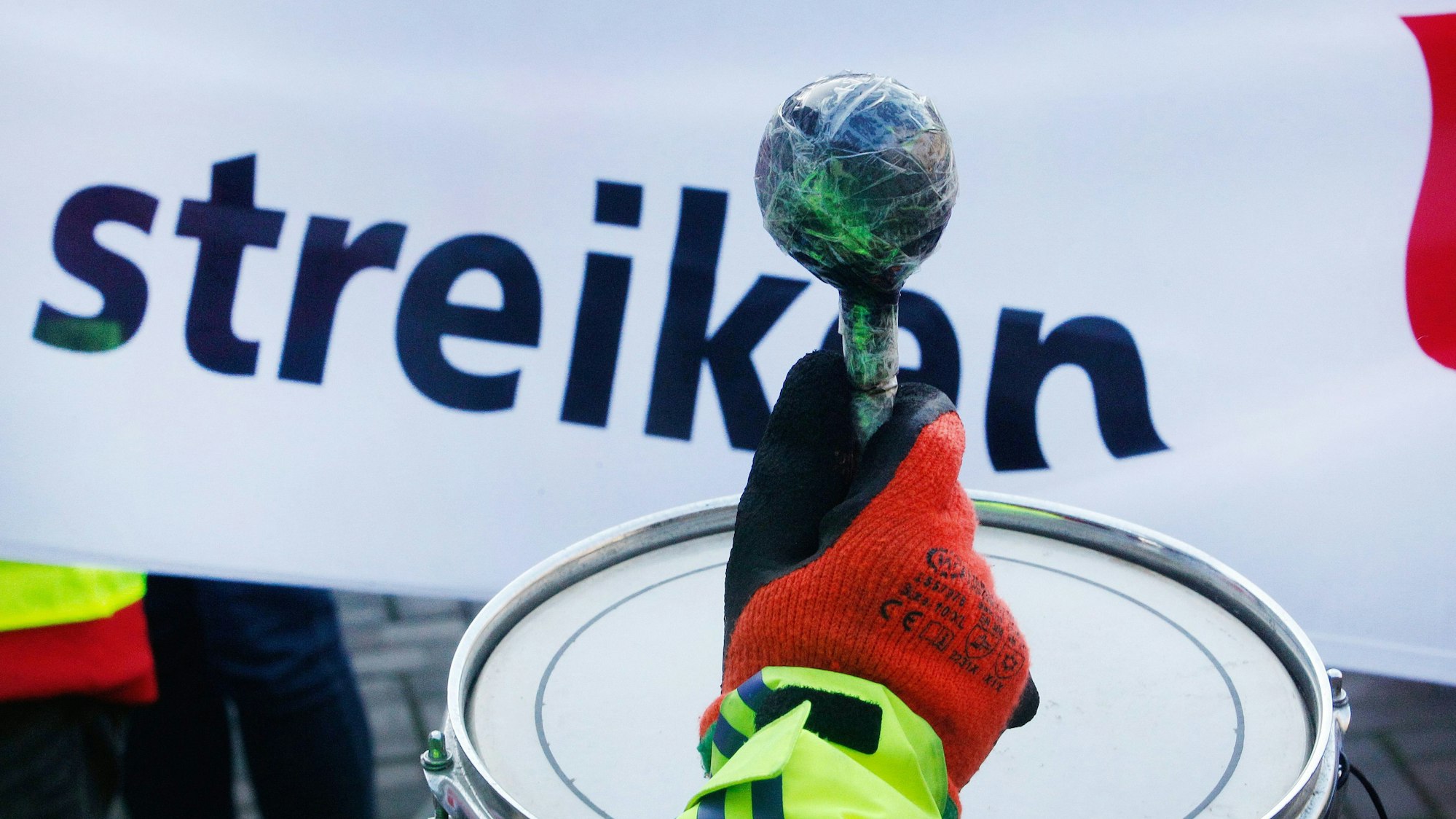 Mit Trommelschlägen beteiligt sich ein Gewerkschaftsmitglied an einer Streik-Kundgebung von Verdi.