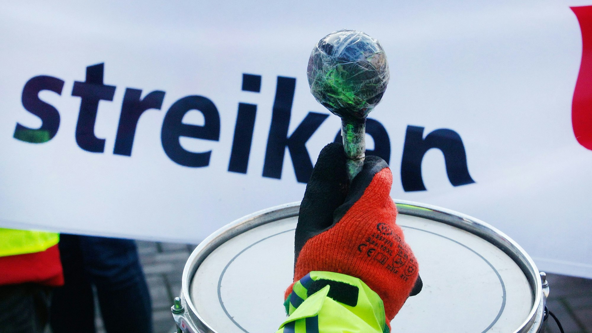 Mit Trommelschlägen beteiligt sich ein Gewerkschaftsmitglied an einer Streik-Kundgebung von Verdi.