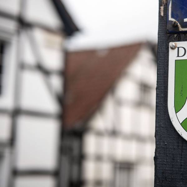 Ein Nordrhein-Westfälisches Denkmal-Schild mit der Aufschrift «Denkmal» ist am Balken eines Fachwerkhauses befestigt.