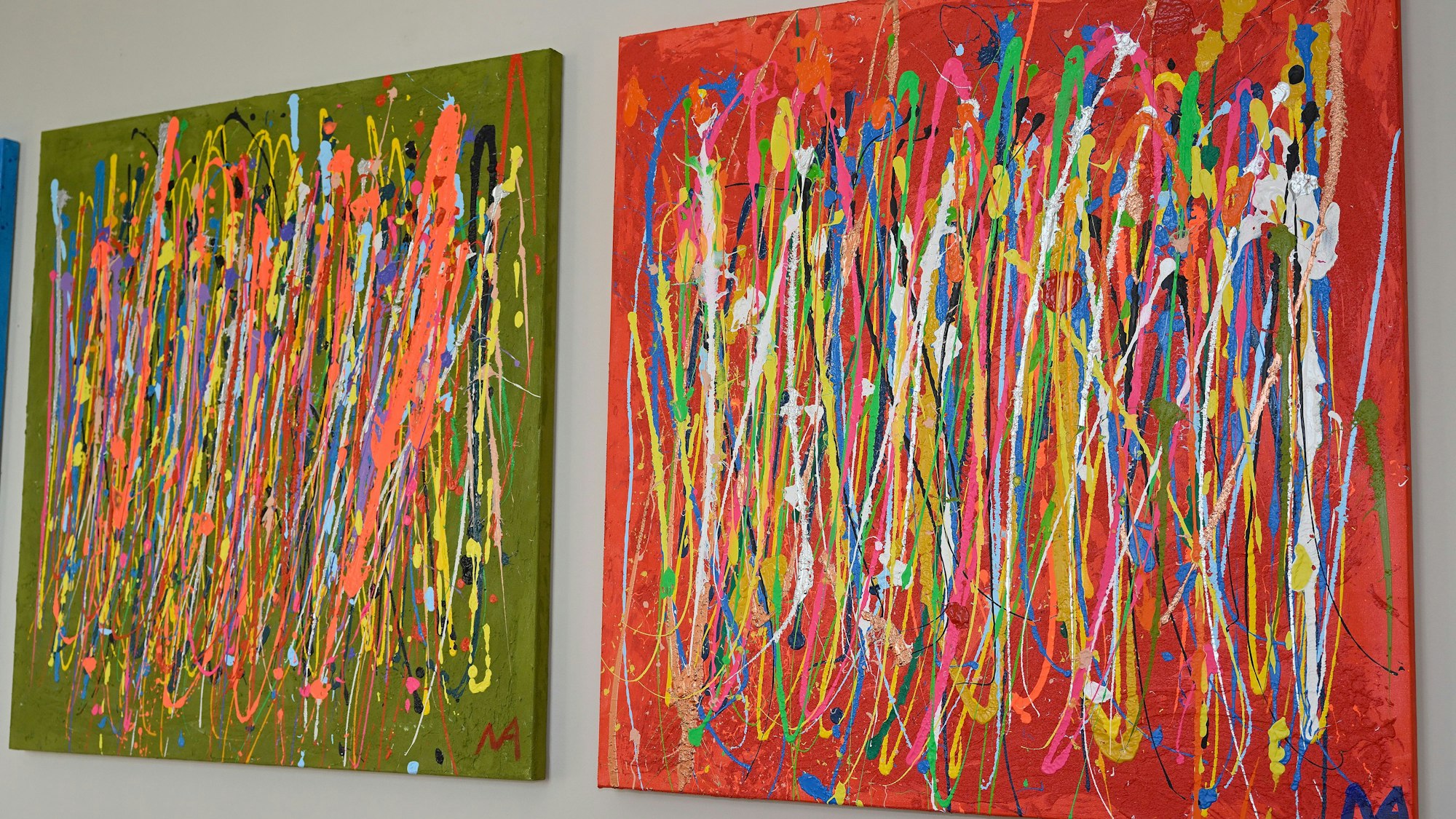 Bilder mit vielen Farben hängen an einer Wand.