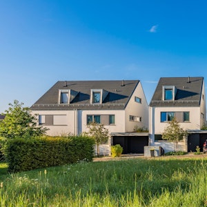 Vier Häuser stehen am Rand einer Wiese und von Garagen.