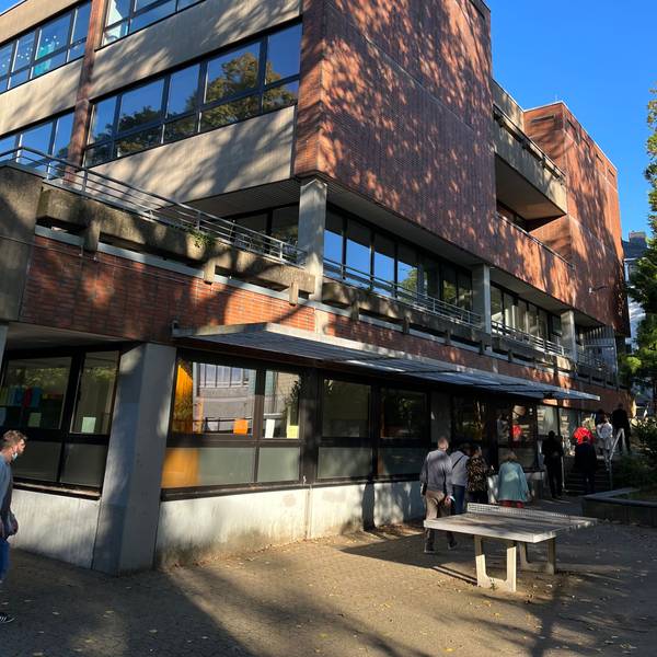 Schüler gehen an einem Schulgebäude entlang.