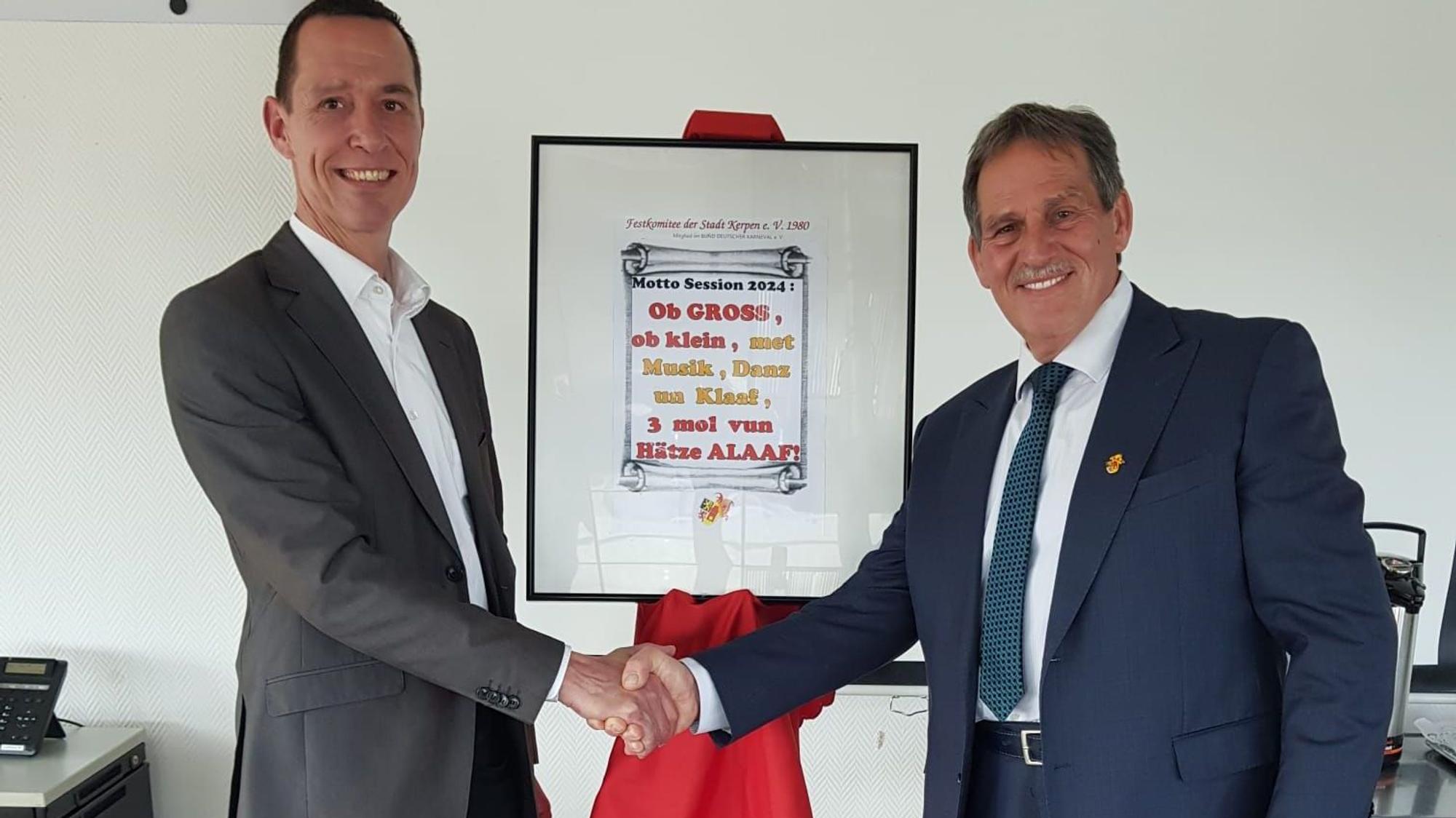 Das Foto zeigt Kerpens Bürgermeister Dieter Spürck und den Karnevalisten Jürgen Mein mit dem neuen Sessionsmotto.