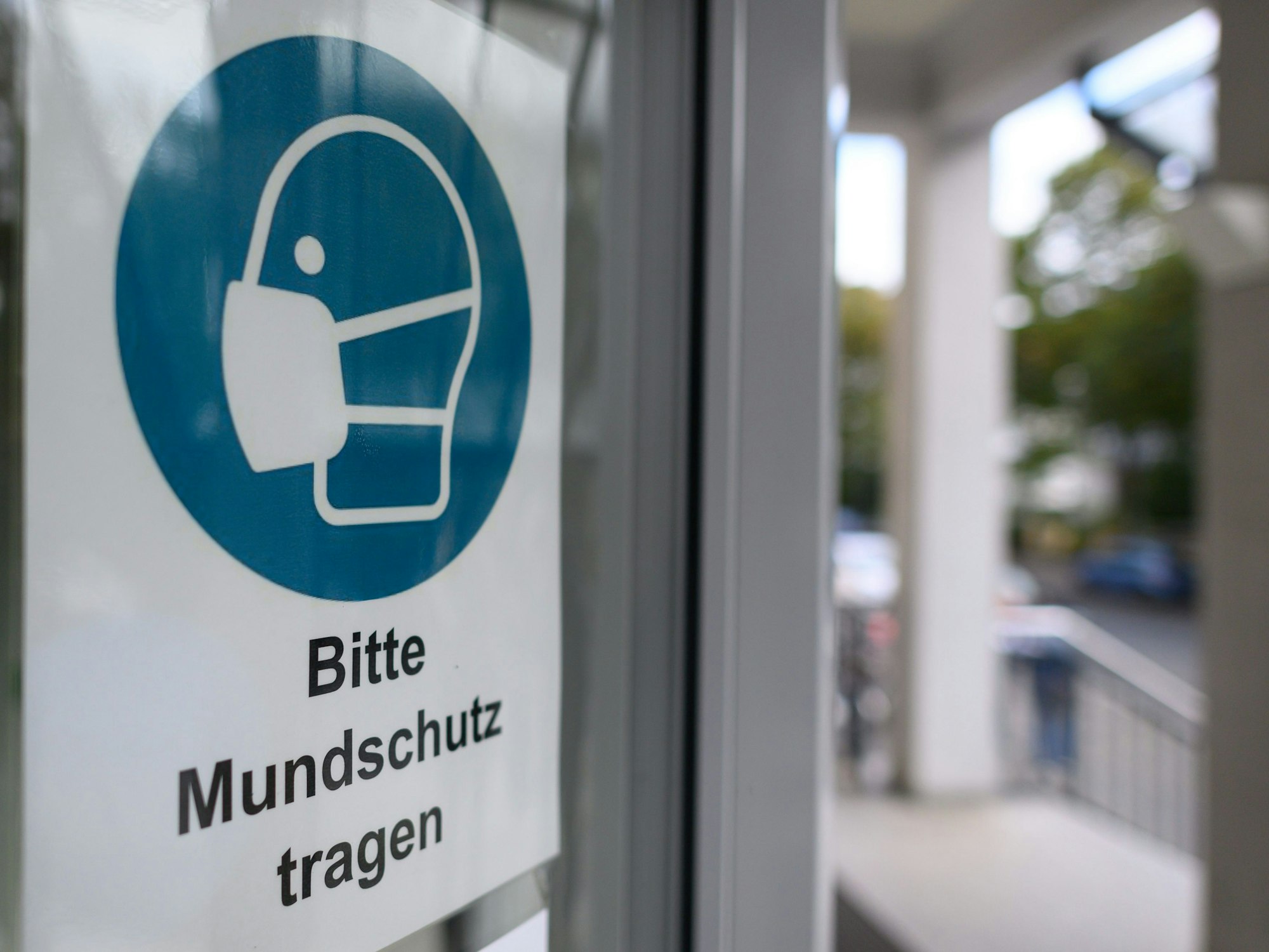 Ein Schild "Bitte Mundschutz tragen" am Eingang eines Krankenhauses.