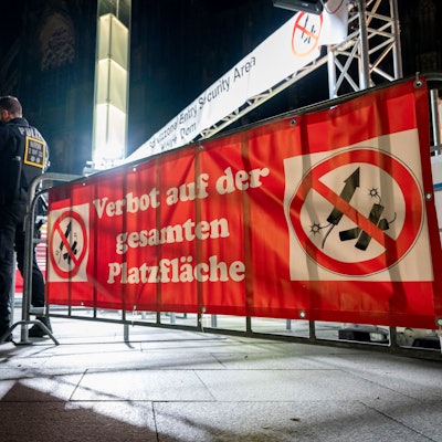 Polizisten stehen an Silvester vor einem Schild, das auf eine Böllerverbotszone hinweist.