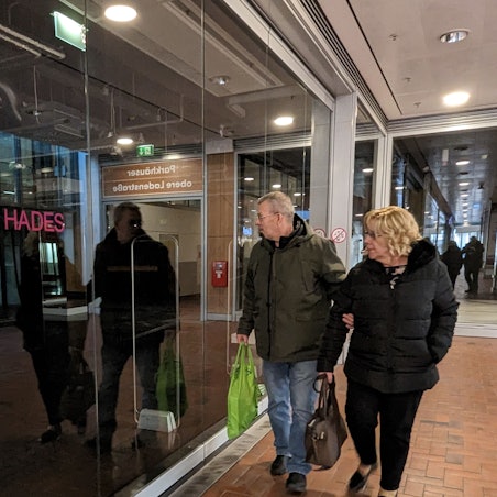 Das Foto zeigt zwei Passanten vor dem leerstehenden Ladenlokal des Textilhändlers Olymp & Hades.