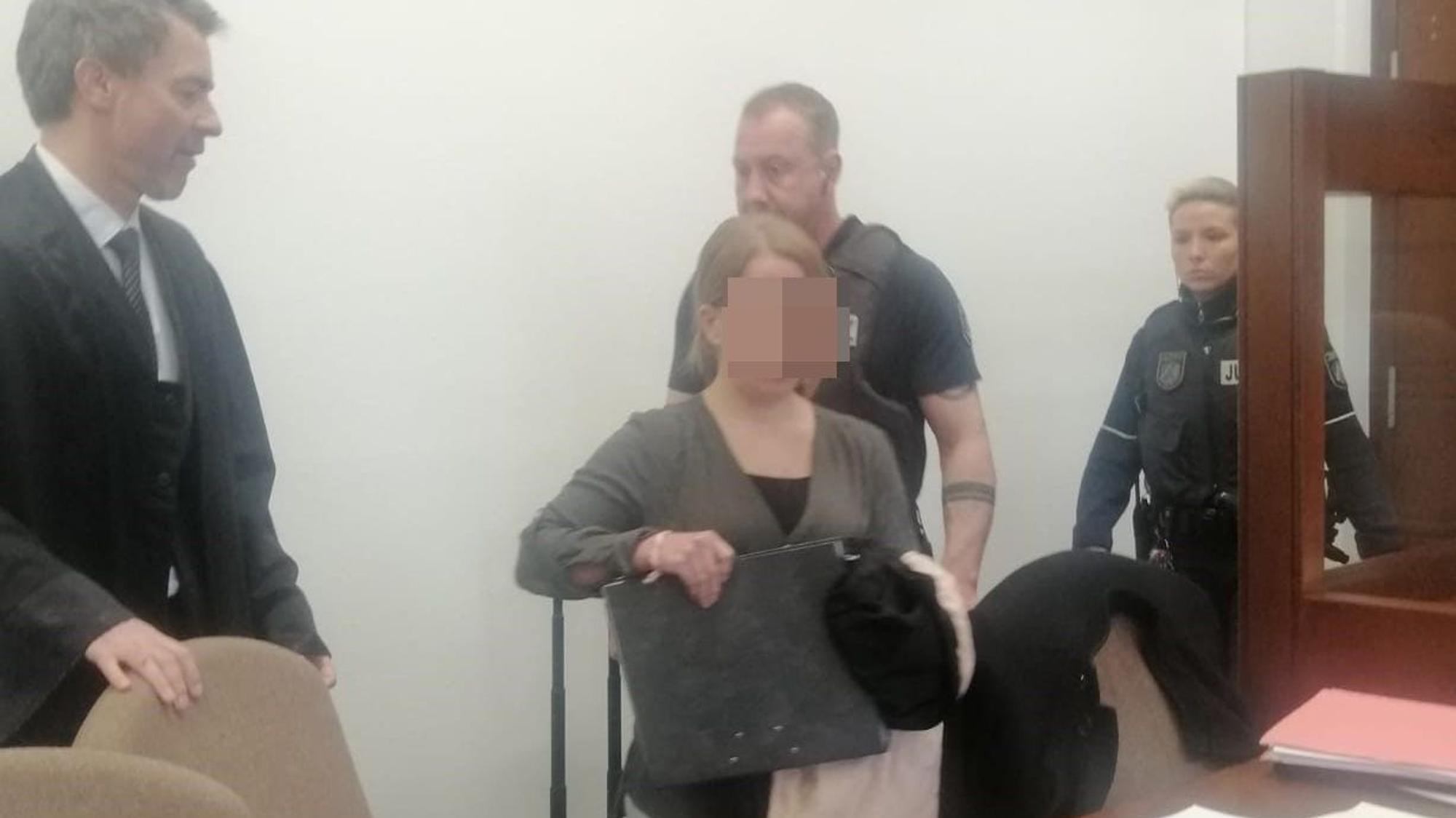 Die Angeklagte wird von Justizangestellten in den Gerichtssaal geführt.