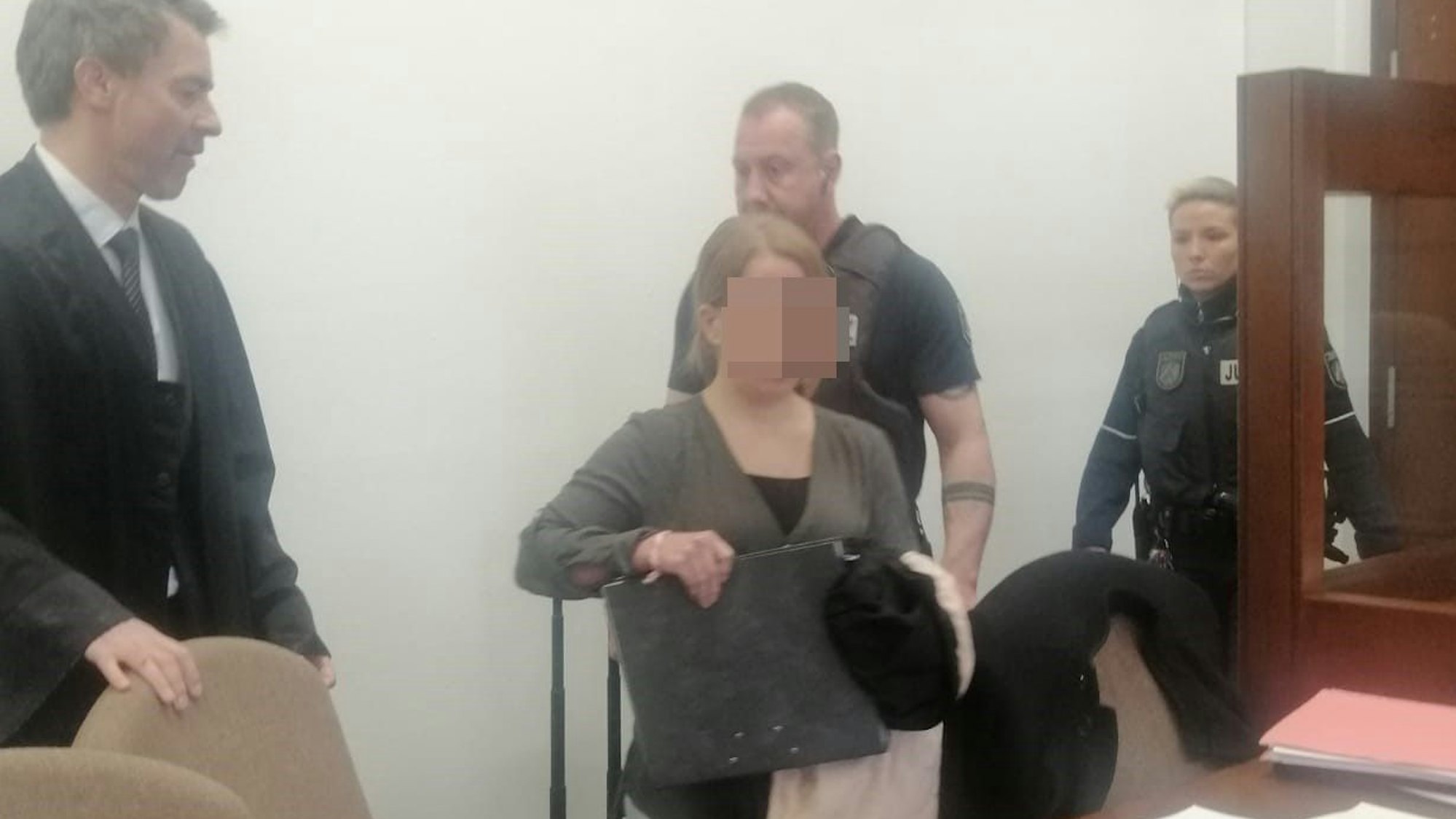 Die Angeklagte wird von Justizangestellten in den Gerichtssaal geführt.