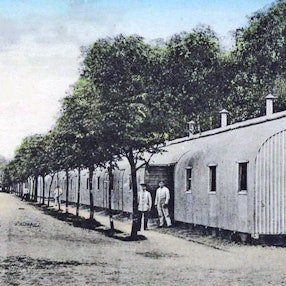 Blick auf eine ältere Zeichnung von Baracken, die zwischen Bäumen stehen.