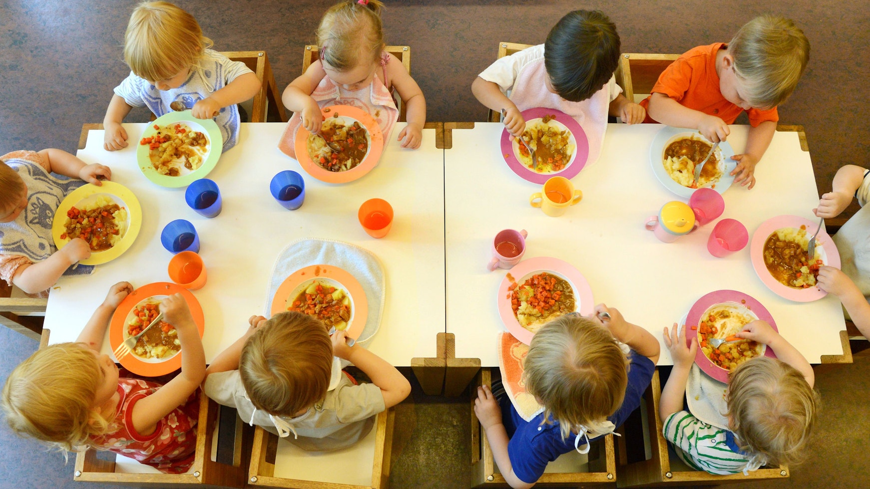 Kinder sitzen in einer Kindertageseinrichtung in Leipzig beim Mittagessen.