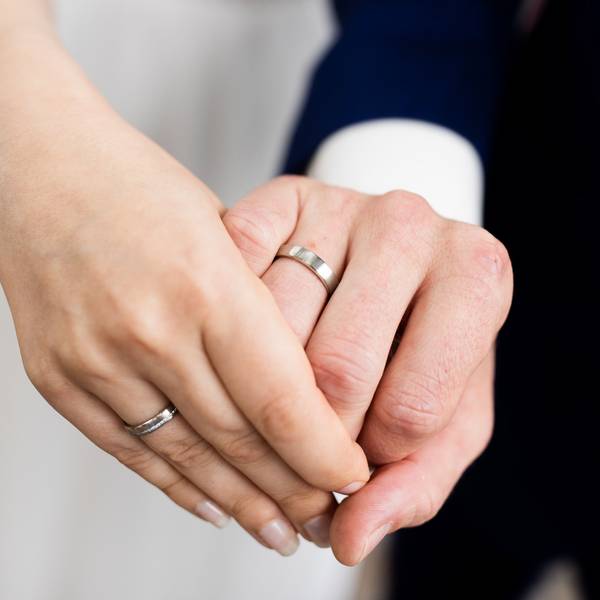 Auf dem Foto ist ein frisch vermähltes Brautpaar zu sehen. Es zeigt nach der Eheschließung im Rathaus seine Eheringe.