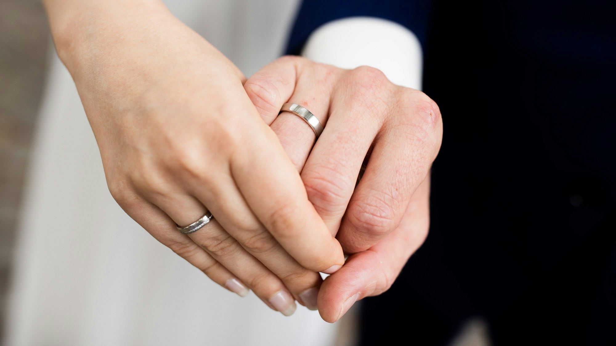 Auf dem Foto ist ein frisch vermähltes Brautpaar zu sehen. Es zeigt nach der Eheschließung im Rathaus seine Eheringe.