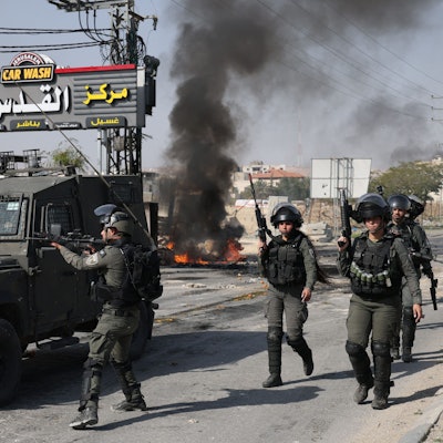 Isrealische Sicherheitskräfte patroullieren eine Straße.