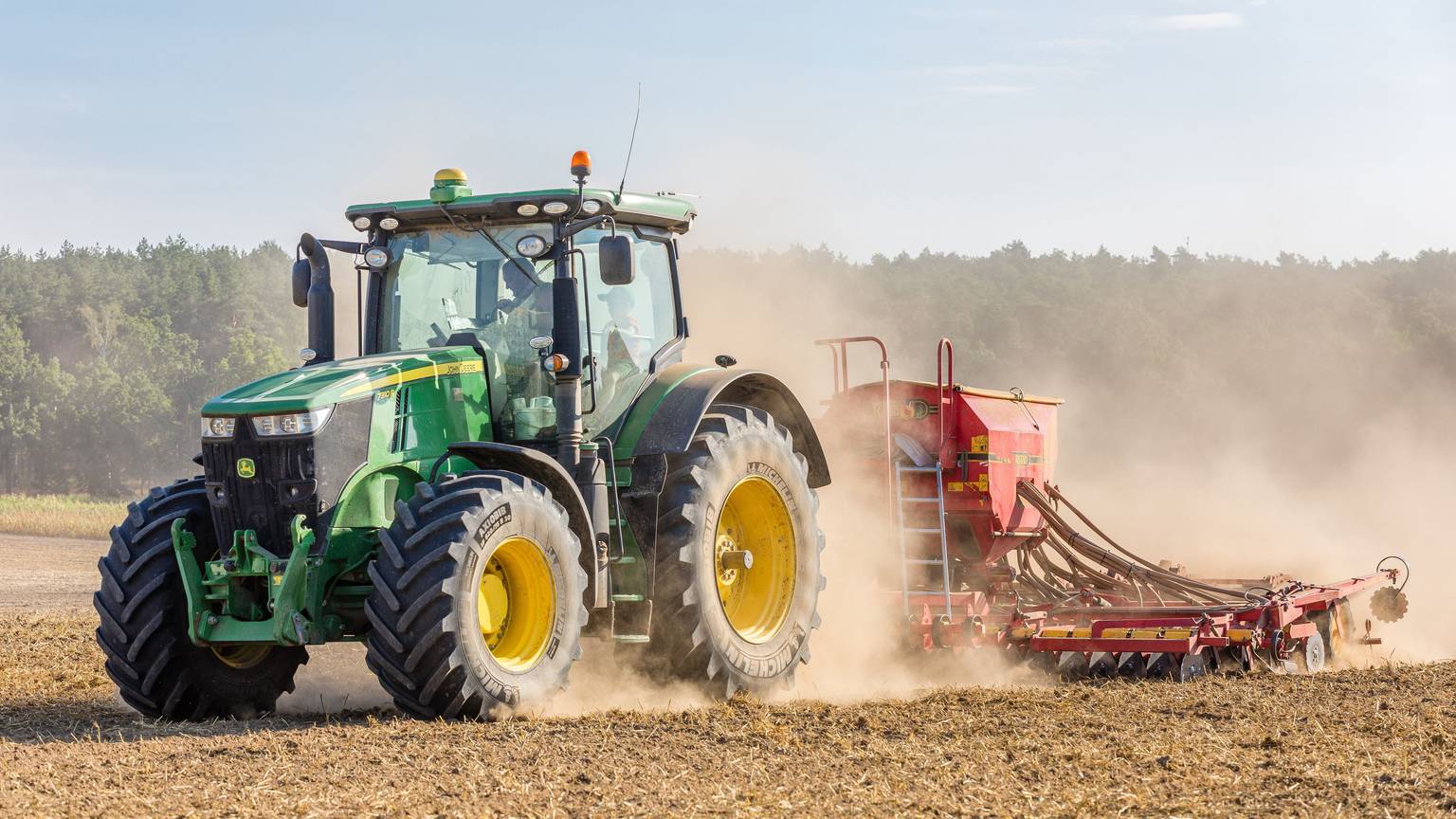 Ein Traktor fährt über trockenes Feld.