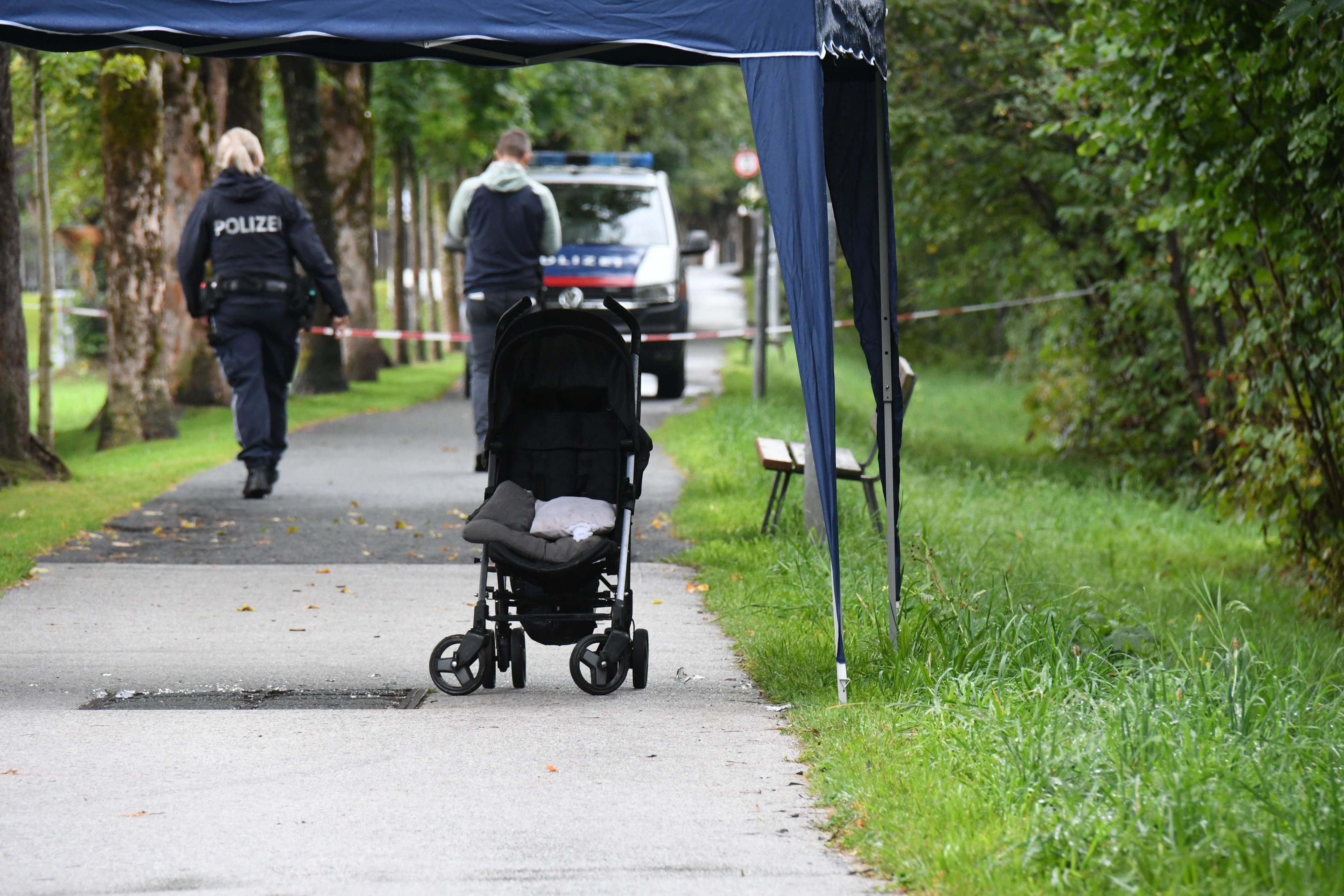 Ein Kinderwagen steht auf einem mit Absperrband gesperrten Gehweg.