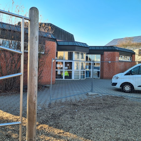 Blick auf die Halle an der Ulrichschule in Sindorf, vorne steht ein Bauzaun.