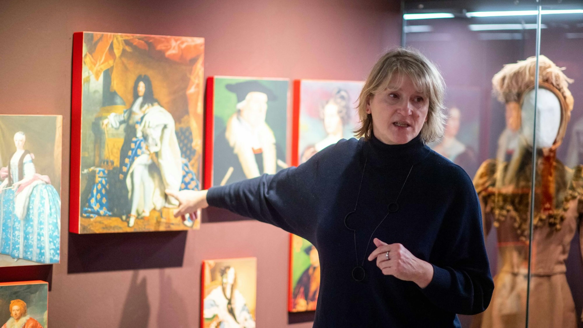 Claudia Gottfried steht vor mehreren Gemälden.