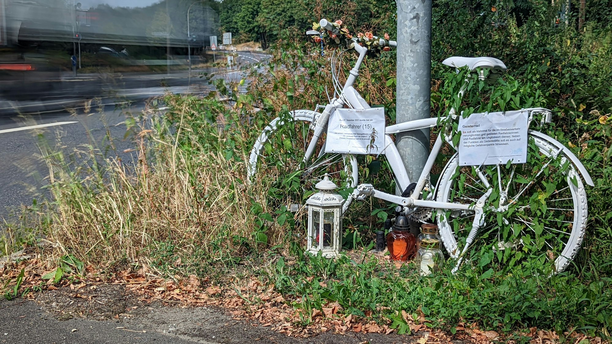Das Foto zeigt ein symbolisches Geisterrad an der Frechener Straße vor der Kreuzung Sudetenstraße erinnert an den 15-jährigen Radfahrer, der dort im Dezember 2021 von einem abbiegenden Lkw überrollt und getötet wurde.