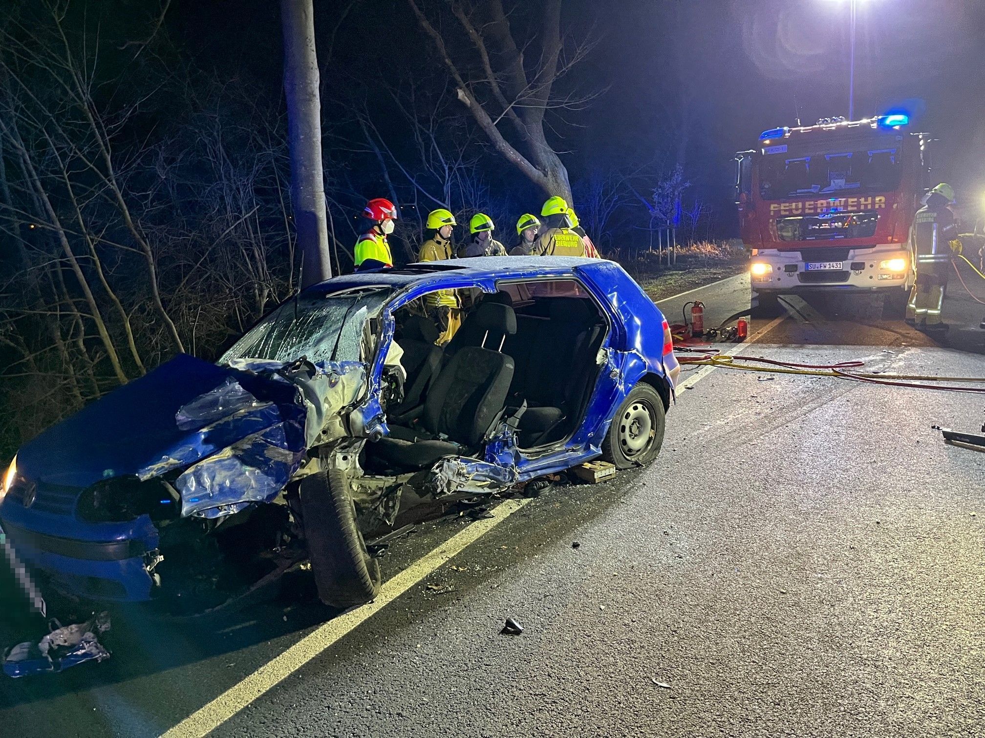 Feuerwehrleute stehen hinter dem Autowrack.