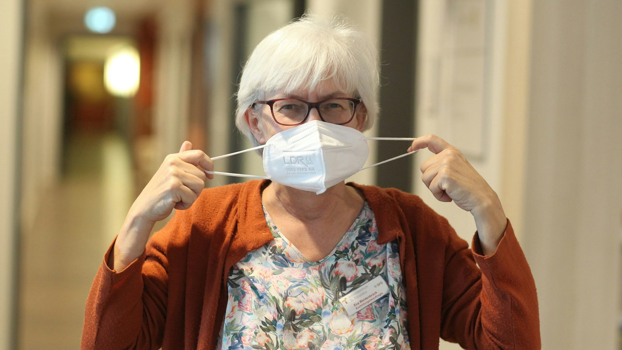 Eine Pflegerin legt die Maske ab.