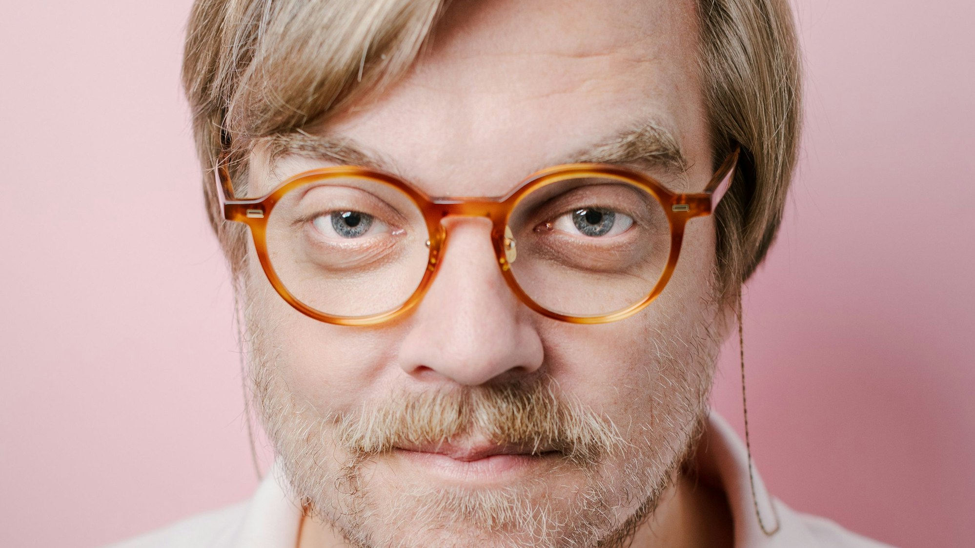 Nilz Bokelberg vor einem rosanen Hintergrund