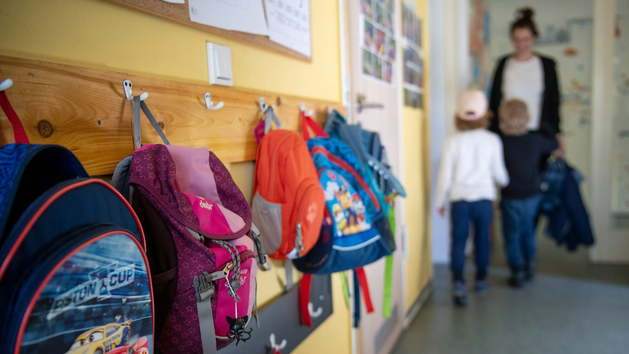 Kinderrucksäcke hängen im Eingangsbereich eines Kindergartens.