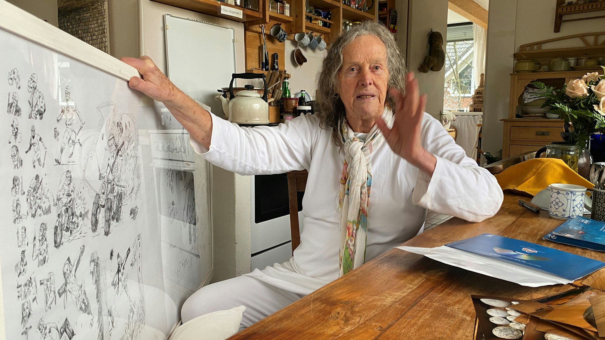 Mary Bauermeister sitzt an einem Tisch in ihrem Atelier.