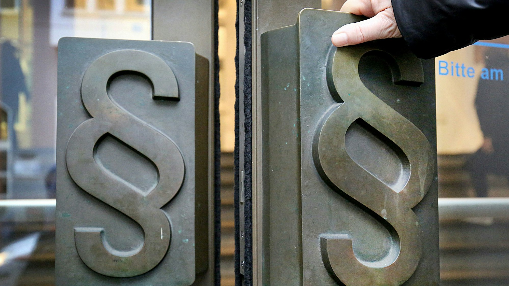 Paragrafen-Symbole sind an Türgriffen am Eingang zum Bonner Landgericht angebracht.