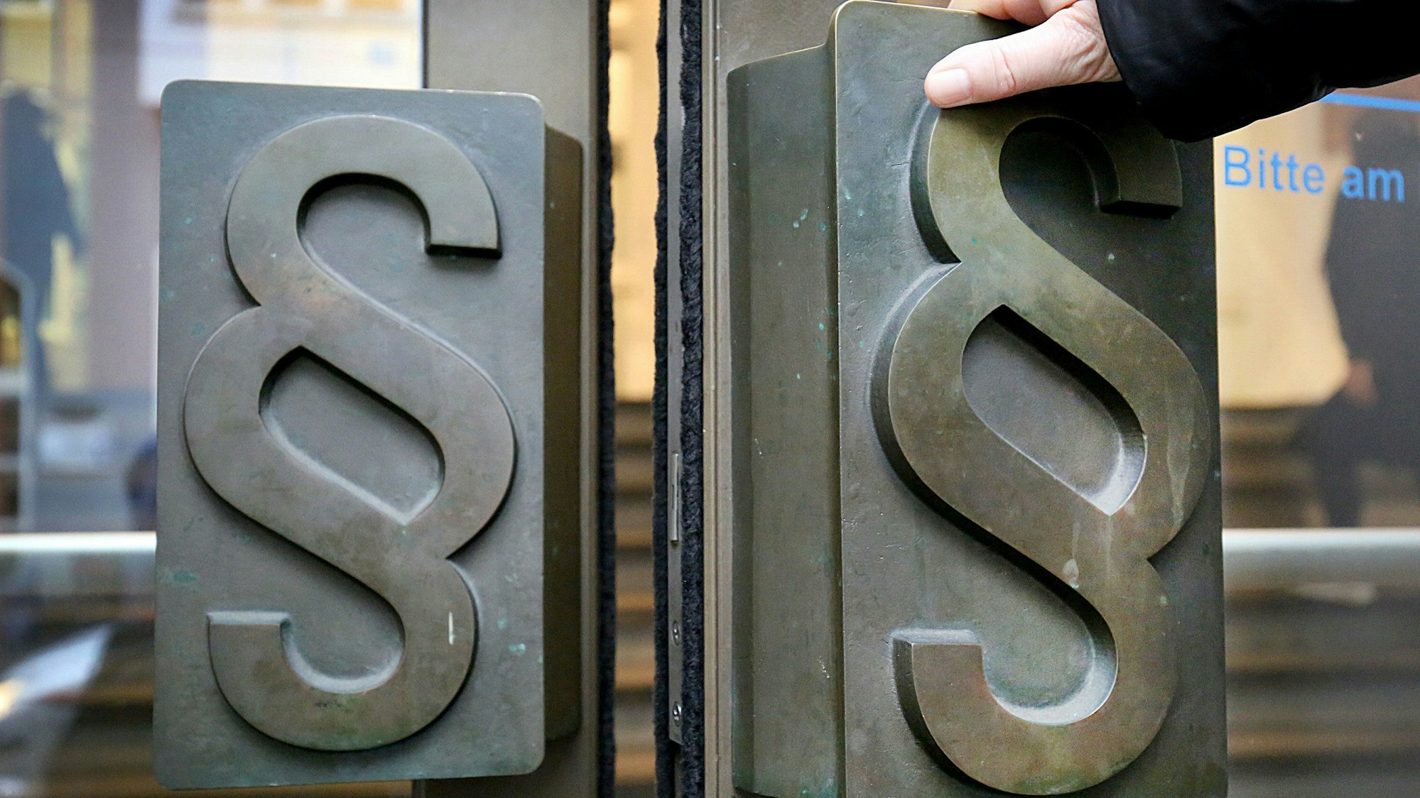 Paragrafen-Symbole sind an Türgriffen am Eingang zum Landgericht in Bonn angebracht.