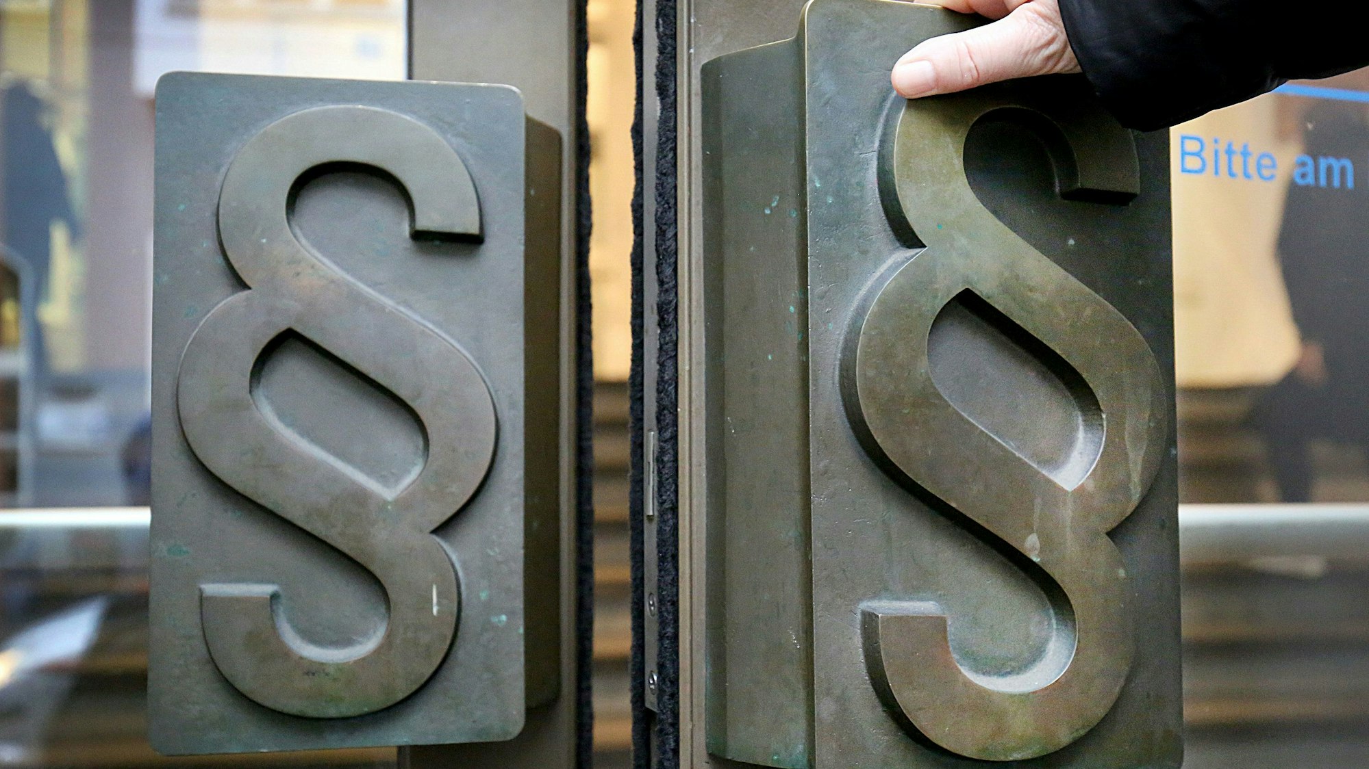 ARCHIV - 21.11.2017, Nordrhein-Westfalen, Bonn: Paragrafen-Symbole sind an Türgriffen am Eingang zum Landgericht angebracht. Nach der Tötung einer 86-jährigen Frau beginnt am 09.05.2021 (9.00 Uhr) vor dem Bonner Landgericht der Prozess gegen ihren Enkel und eine mutmaßliche Mittäterin wegen Mordes. Der 35-Jährige soll seine Großmutter laut Anklage im vergangenen September in ihrem Garten in Bonn erwürgt haben. (zu dpa: «86-Jährige getötet - Enkel wegen Mordes vor Gericht») Foto: Oliver Berg/dpa +++ dpa-Bildfunk +++