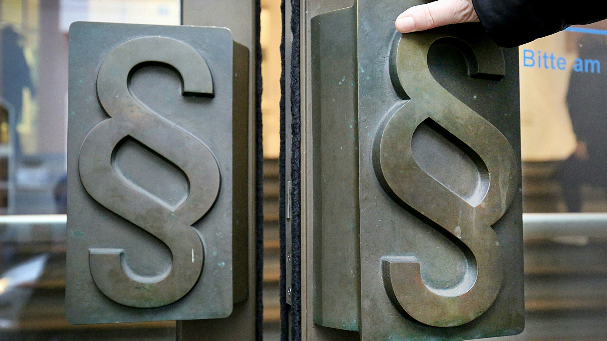 Paragrafenzeichen auf den Türgriffen am Haupteingang zu einem Verwaltungsgebäude.