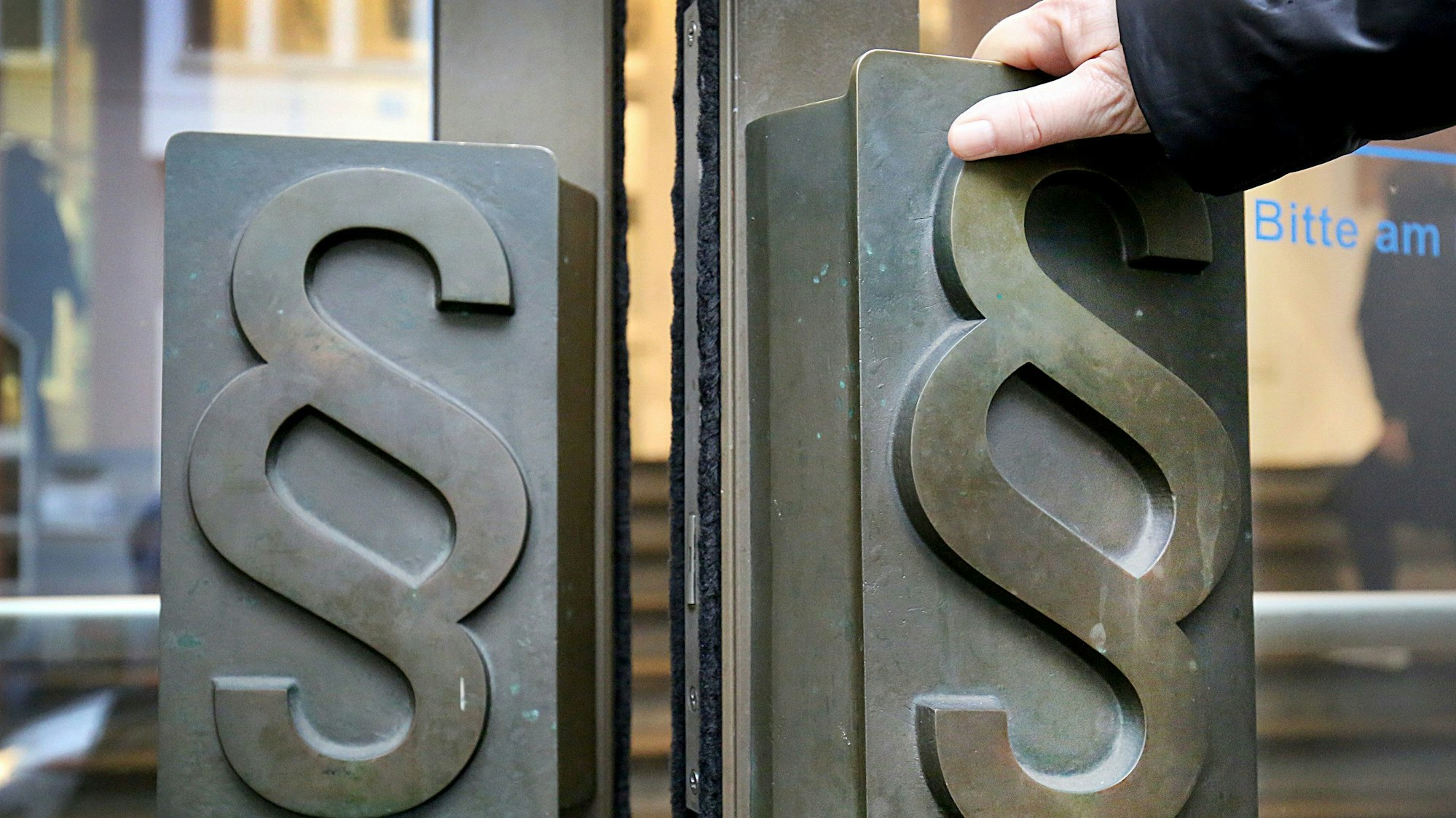 Paragrafen-Symbole sind an Türgriffen am Eingang zum Landgericht.