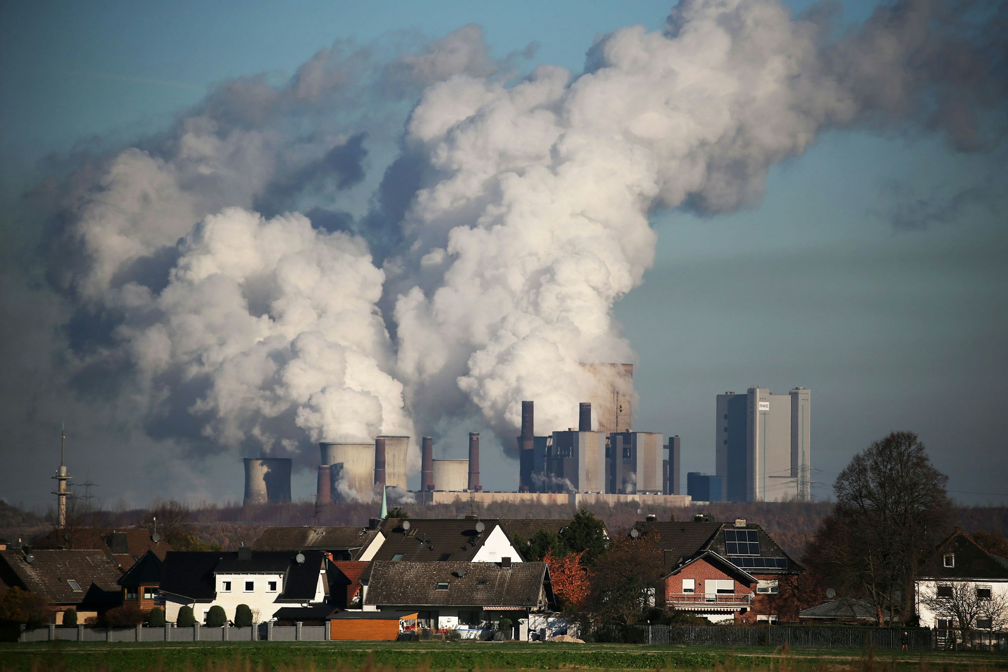 Hinter einer Wohnsiedlung bei Bergheim steigt Dampf aus dem Braunkohlekraftwerk Niederaußem des Energieversorgungskonzerns RWE.