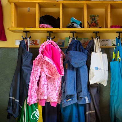 Jacken und Taschen hängen im Eingangsbereich in einem Kindergarten.