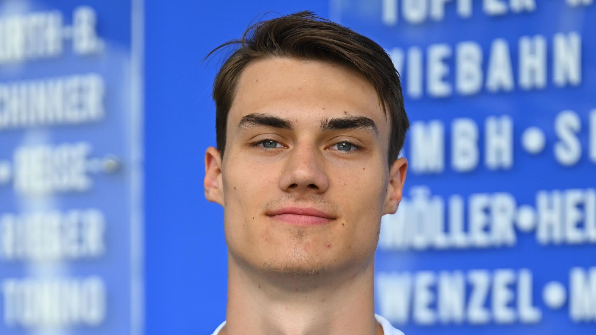 Der Handballer Miro Schluroff ist im Porträt zu sehen. Er trägt ein blau-weißes Trikot des Handballvereins VfL Gummersbach.
