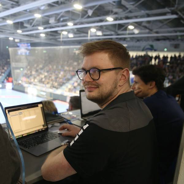 Jan Schwenzfeier sitzt während eines Handballspiels in der Schwalbe-Arena an einem Laptop.