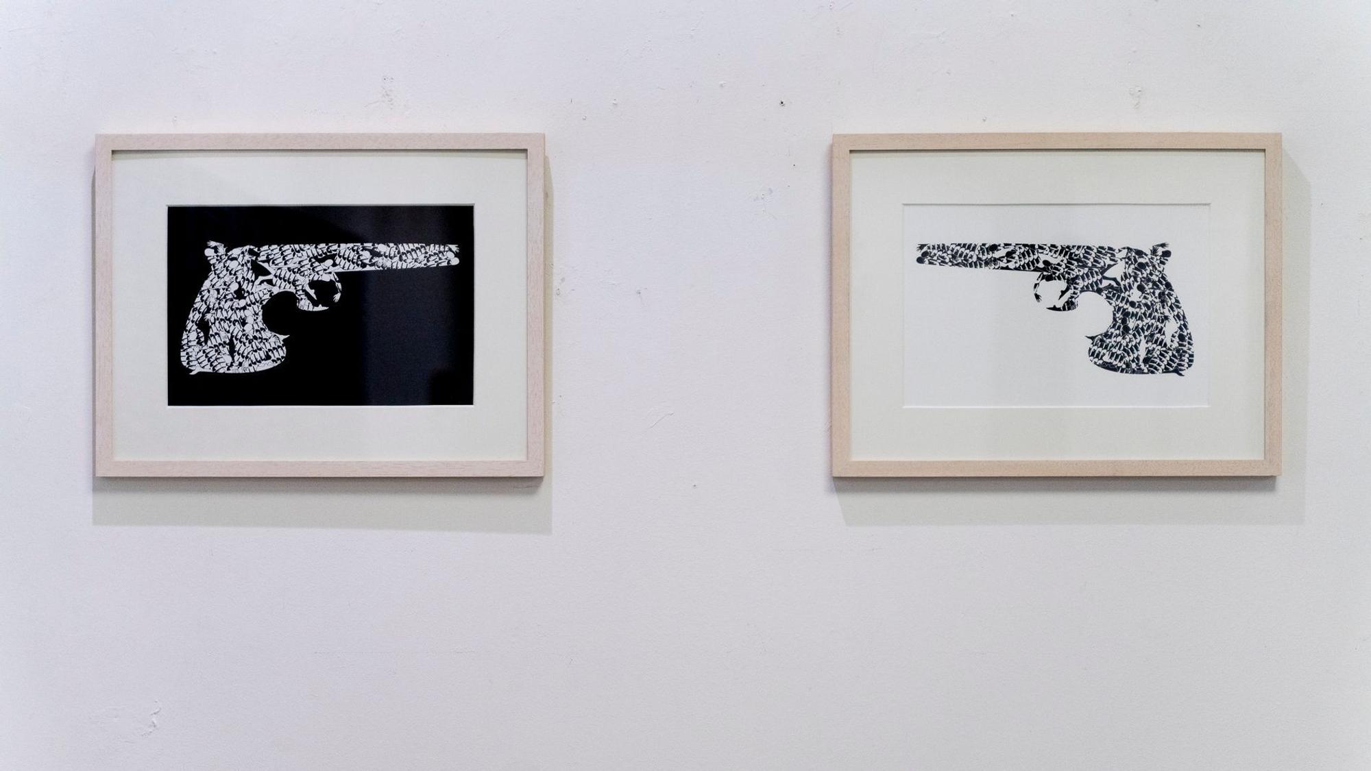 Zwei Bilder, die Pistolen zeigen, hängen an einer Wand.