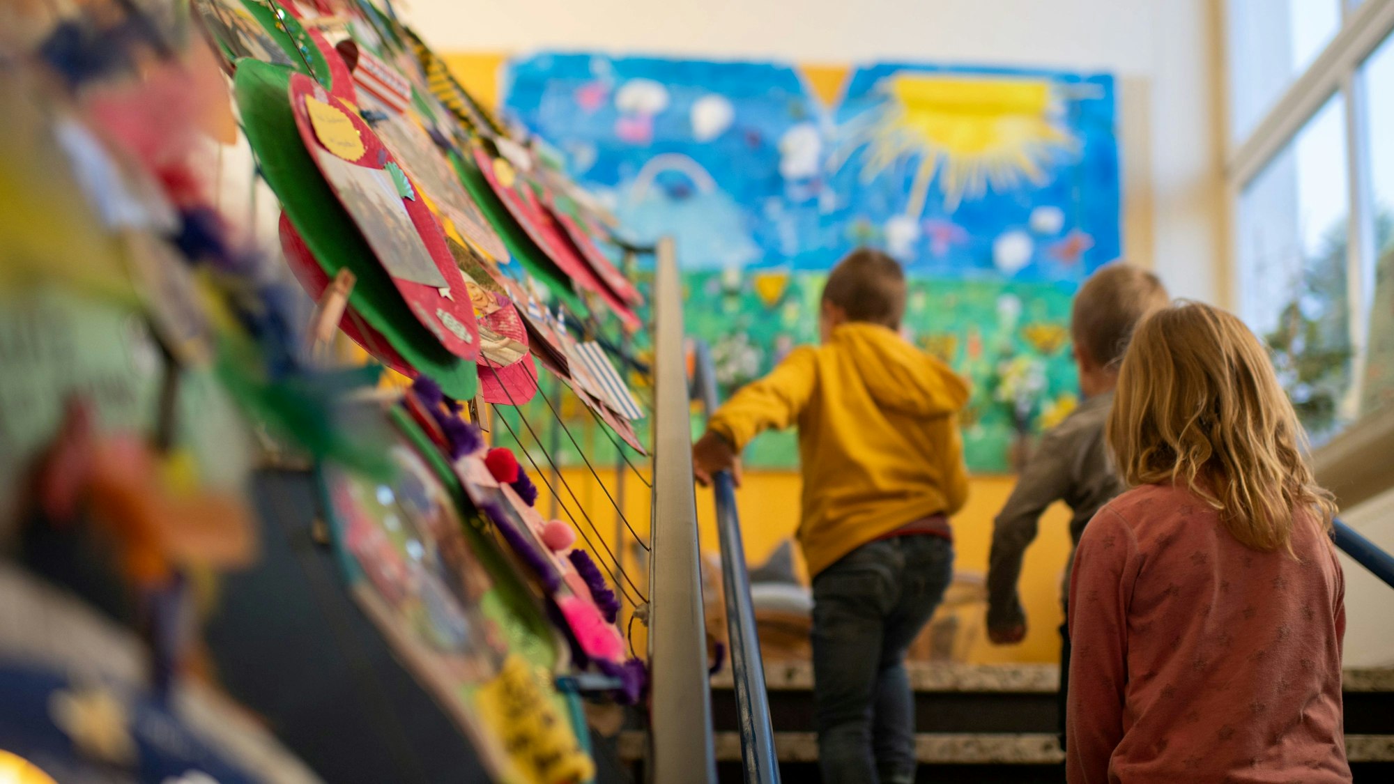 Drei Kindergartenkindern gehen die Treppe in einer Einrichtung hinauf.